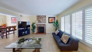 Una sala de estar con chimenea, sofá, televisor y comedor.