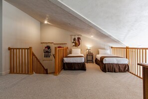 Ein Schlafzimmer mit zwei Betten, einer Holztreppe und einer Decke mit freiliegenden Balken.