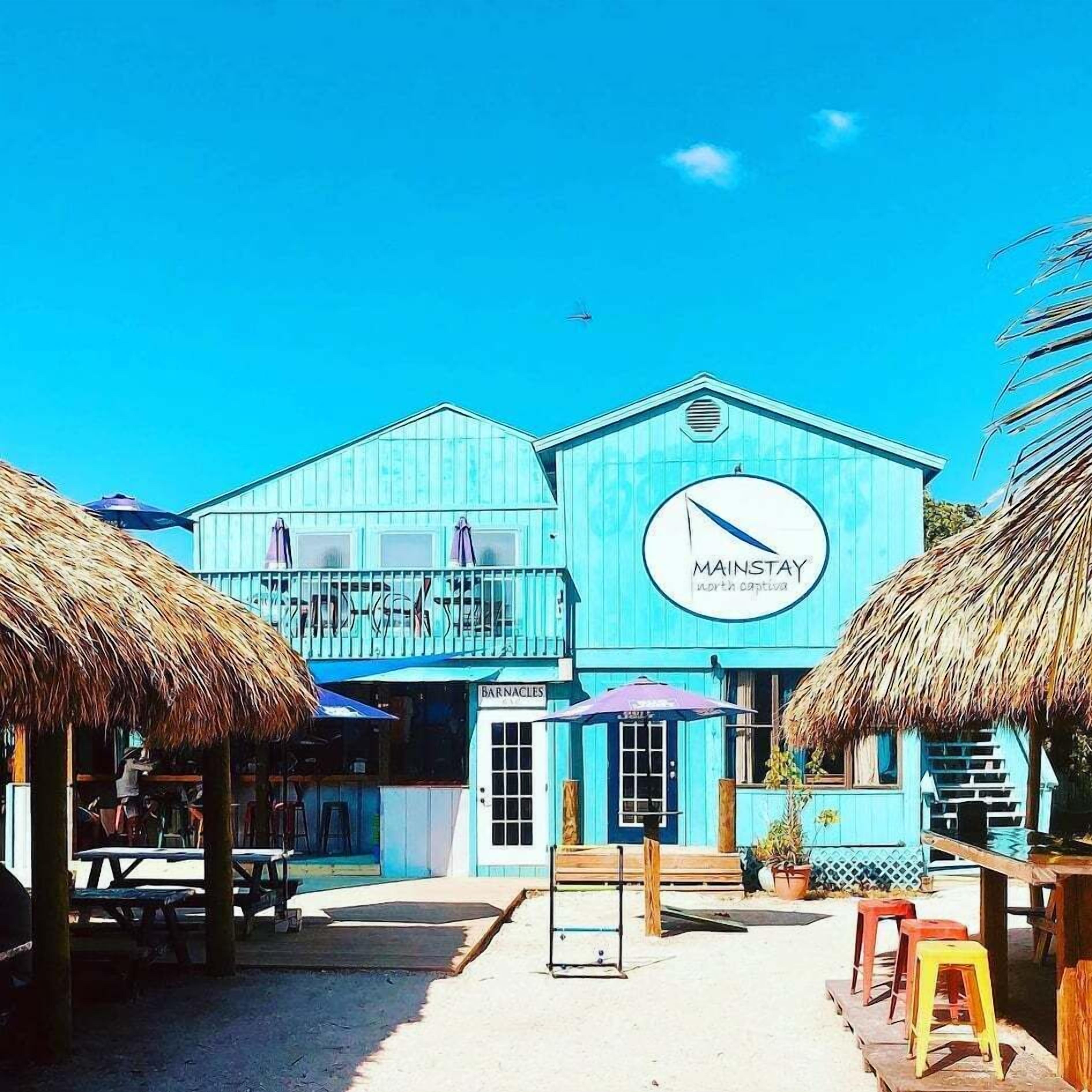 Un edificio blu con un cartello che recita 'MAINSTAY' e un cartello con scritto 'BARNACLES' sotto.