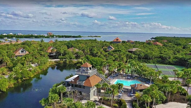 A resort with a central pool, surrounded by lush greenery and multiple buildings. - My Sea Shack~ 1 minute to beach, SH Club access, golf cart (Lee County)