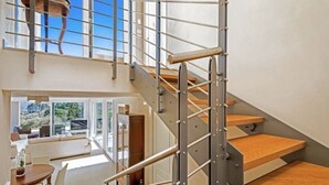 Un intérieur moderne avec un escalier, un coin repas et une vue sur l’extérieur.