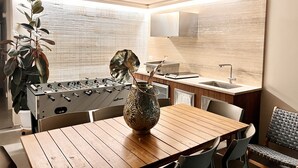 Une cuisine moderne avec une table en bois, un vase décoratif et une table de baby-foot.