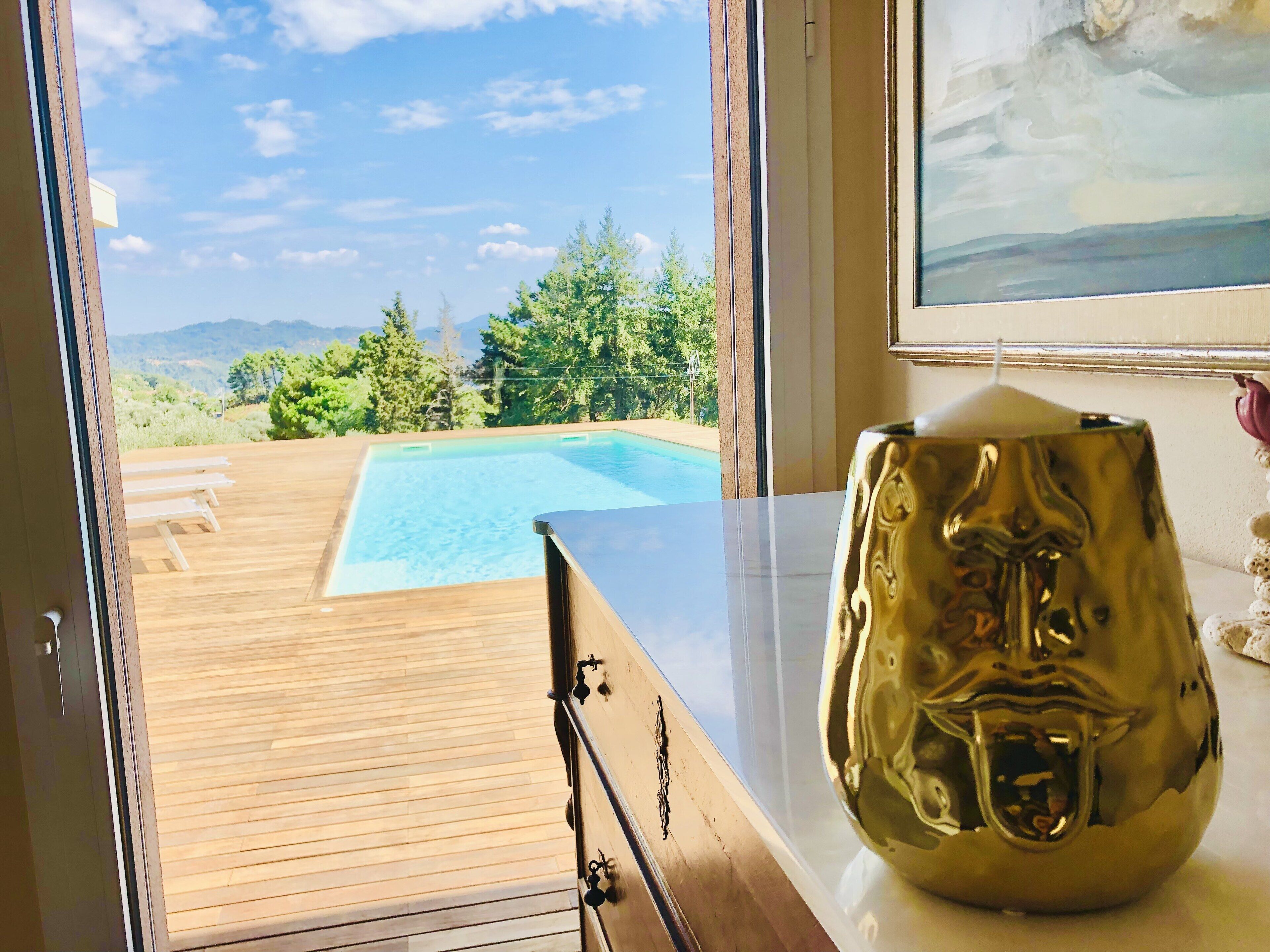 A room with a wooden deck, a view of a swimming pool, and a decorative golden vase.