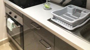 A kitchen with a black stovetop, a marble backsplash, a white countertop, a dish rack, and a small bottle of dish soap. - Diamond Gem Residence is located in proximity to the Dutch/French border (Cole Bay)