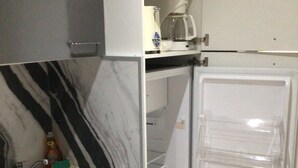A kitchen with a marble backsplash, a stainless steel sink, and a refrigerator with clear shelves. - Diamond Gem Residence is located in proximity to the Dutch/French border (Cole Bay)