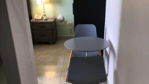A narrow hallway with a round table and two chairs, a bedside table with a lamp, and a wall socket. - Diamond Gem Residence is located in proximity to the Dutch/French border (Cole Bay)