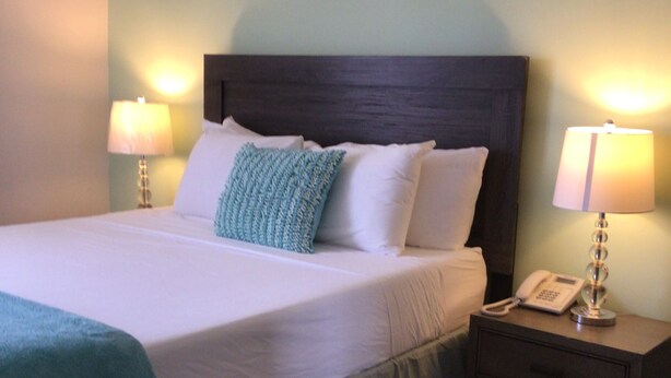 A neatly made bed with a blue blanket, two bedside lamps, and a bedside telephone on a nightstand. - Diamond Gem Residence is located in proximity to the Dutch/French border (Cole Bay)