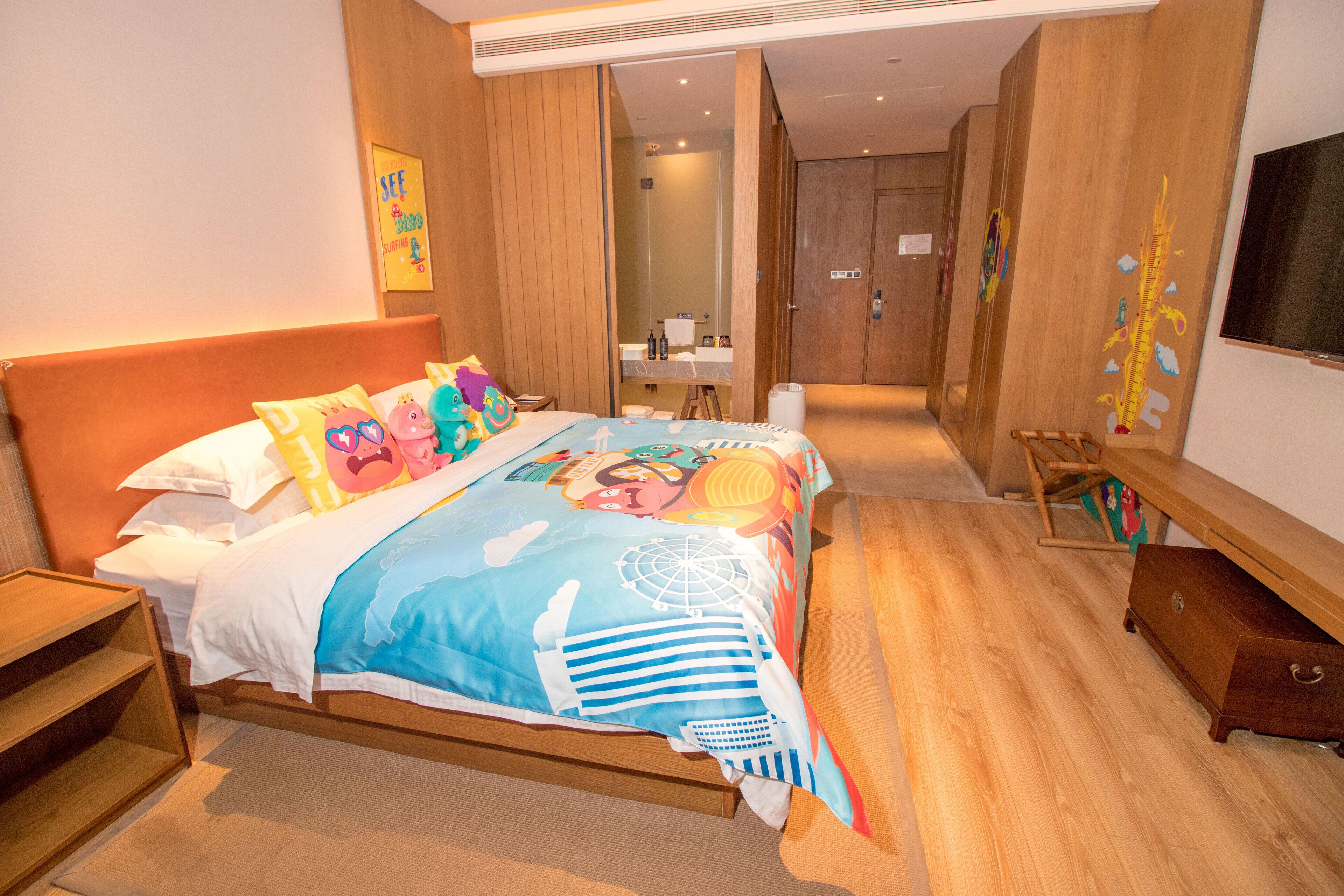 A hotel room with a wooden bed, a wooden dresser, a wooden bench, and a large mirror.