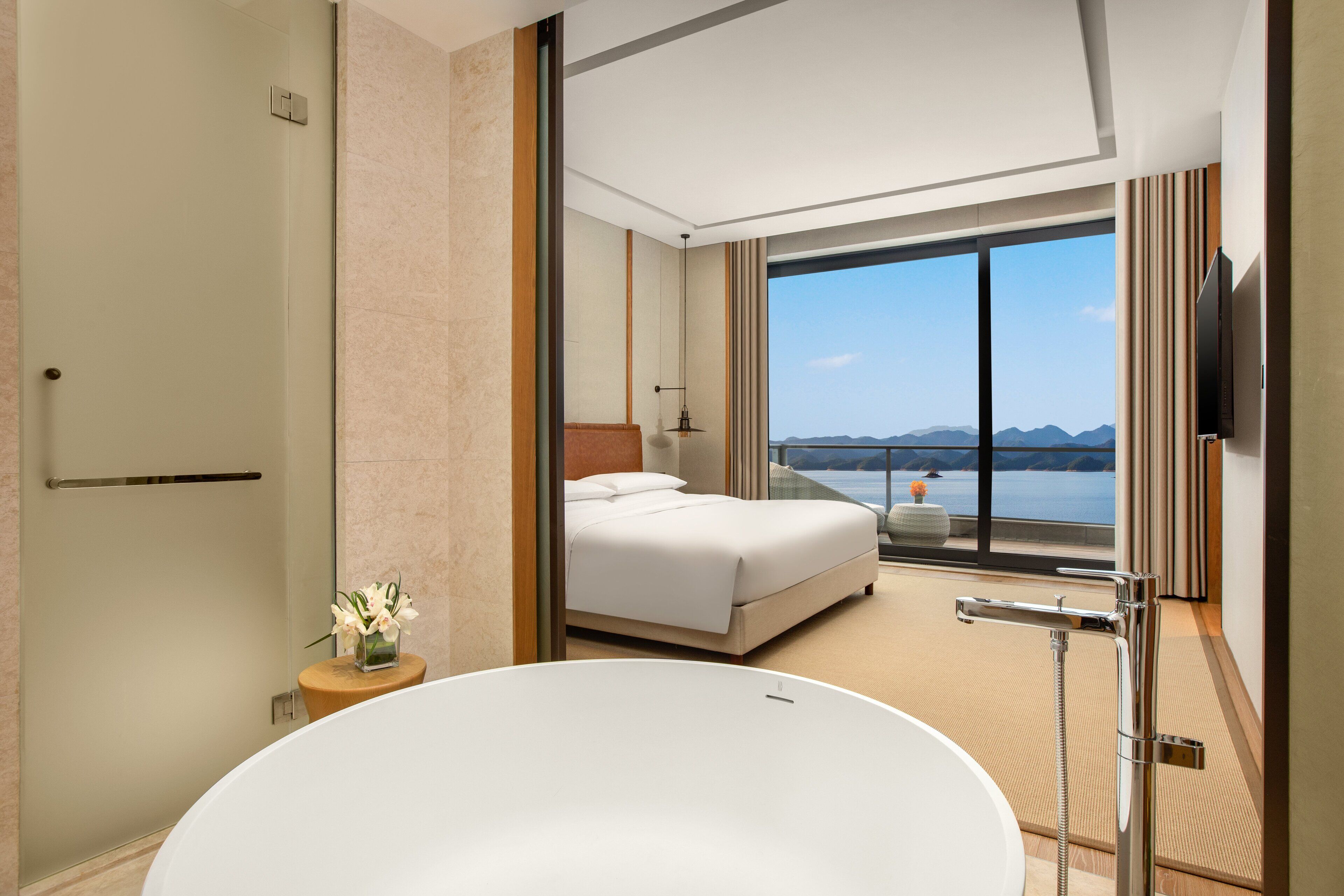 Une chambre d’hôtel moderne avec un grand lit, une baignoire et une vue sur les montagnes.