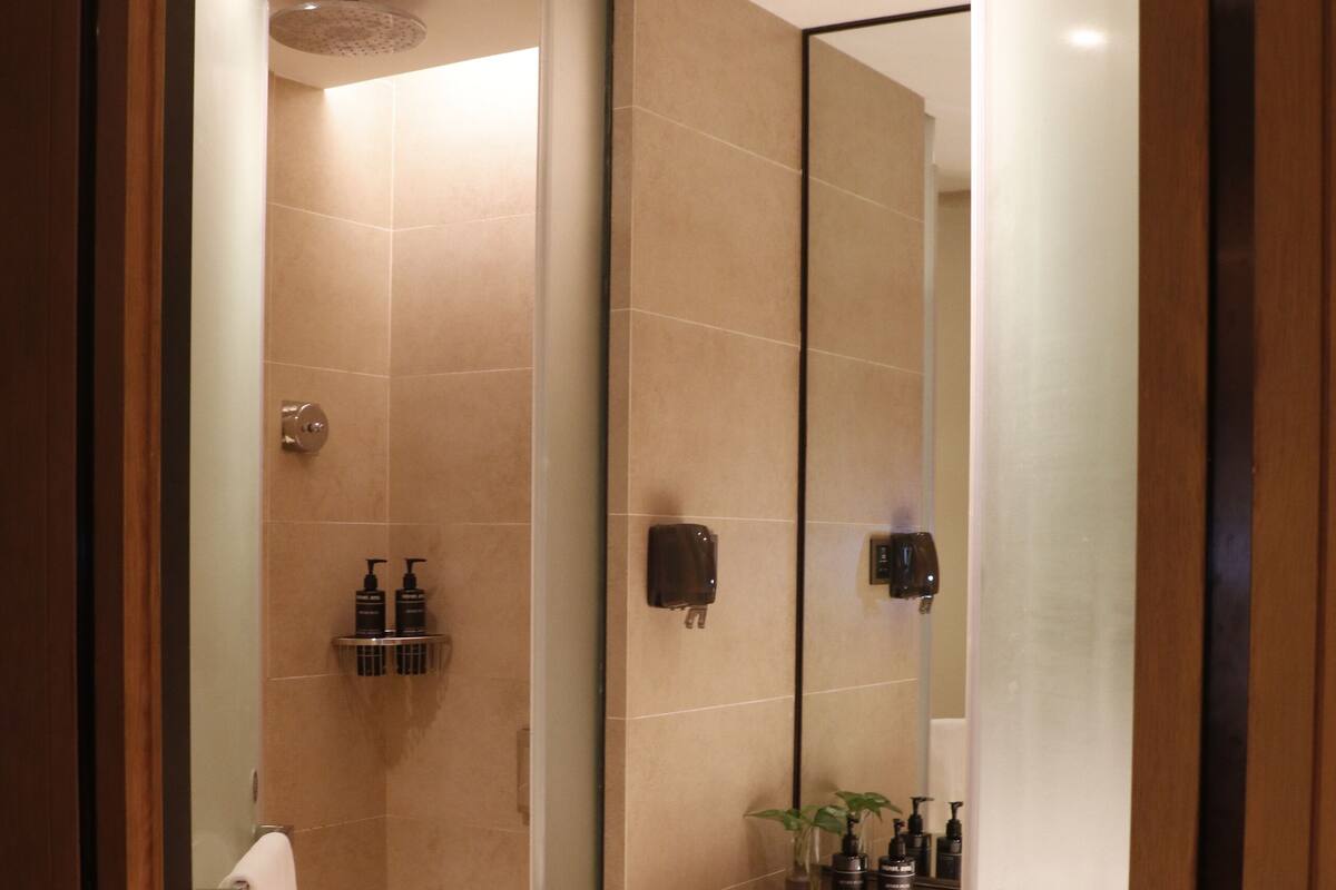 A modern bathroom with a glass-enclosed shower, a vanity with a mirror, and a towel rack.