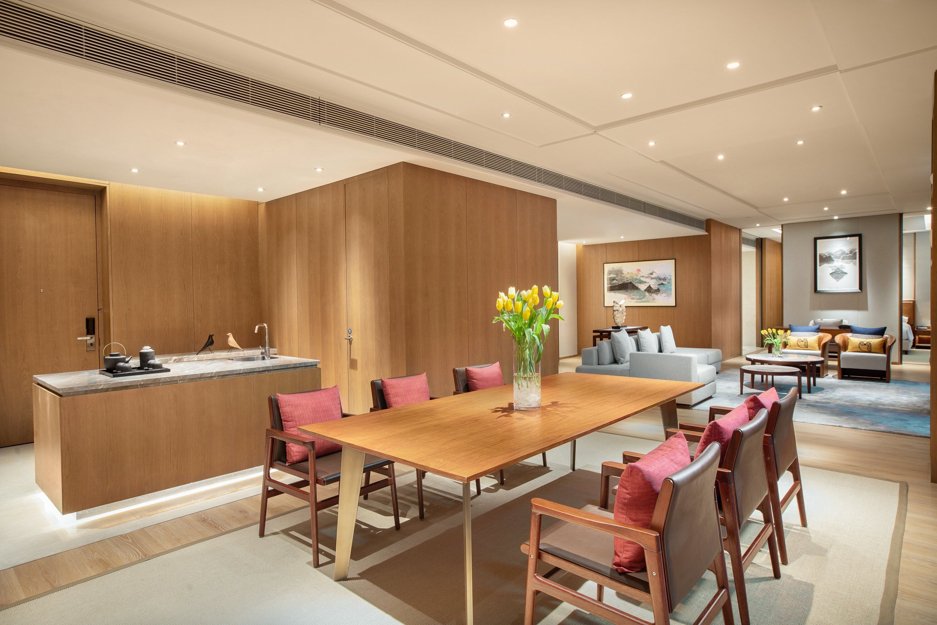 Un comedor moderno con una mesa de madera, sillas y un jarrón de flores.