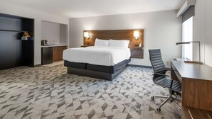 A hotel room with a bed, a desk, a chair, and a kitchenette. - Best Western Plus Harrisonburg (Harrisonburg)