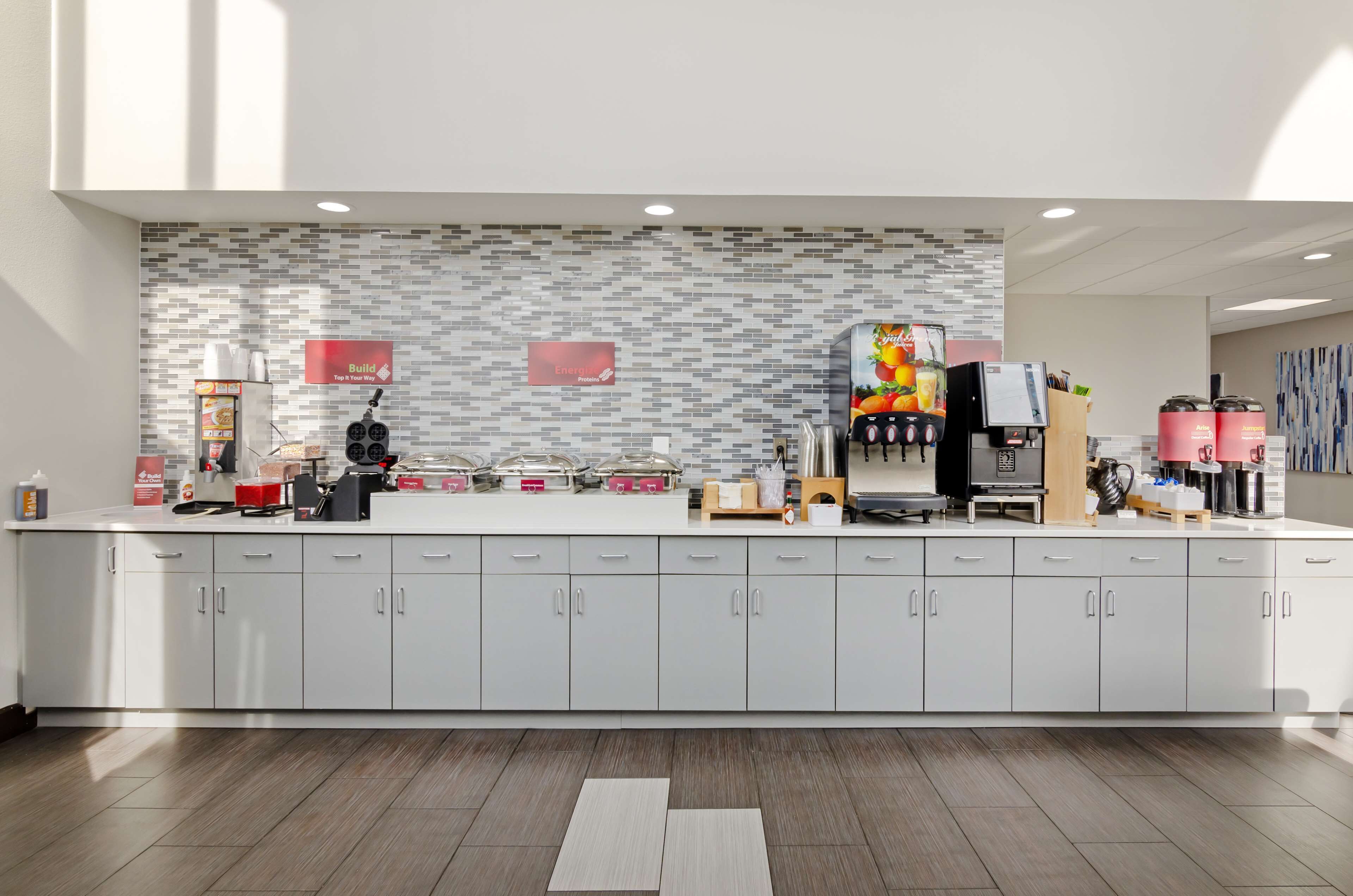 Una cocina moderna con un revoque de azulejos, una cafetera y un dispensador de fruta.