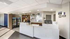 A reception area with a marble counter, a bookshelf, a refrigerator, and a wall-mounted TV. - Best Western Plus Harrisonburg (Harrisonburg)