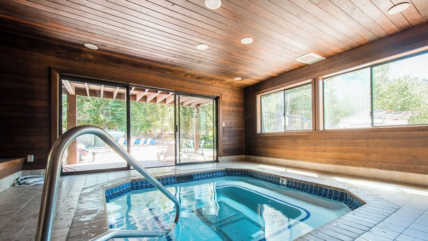 A swimming pool with a wooden ceiling and large windows.