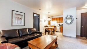 A living room with a black leather sofa, a wooden coffee table, and a framed picture on the wall.