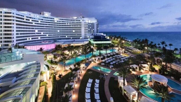 Un gran hotel con varias piscinas, una zona de playa y vistas al océano.