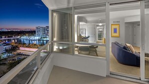 Un apartamento moderno con balcón que da a una vista panorámica de la ciudad al anochecer.