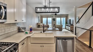 A modern kitchen with a dishwasher, stove, and a dining area with a view of the ocean.