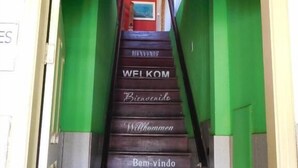 A staircase with multilingual 'Welcome' signs leading to rooms. - Vibe hostel Paraty (Paraty)