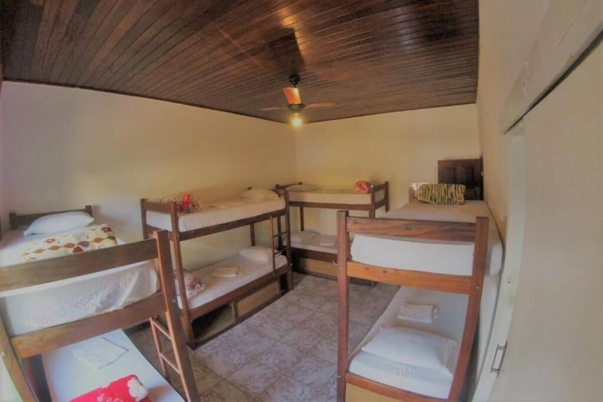 A dormitory room with bunk beds, a ceiling fan, and a tiled floor.