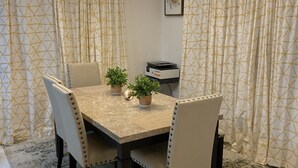 A dining area with a rectangular table, four chairs, a potted plant, and a ceiling light fixture. - Sapphire Villa Near the Sea-Entire Home (Nassau)