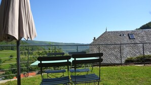 Una terraza con mobiliario exterior y vistas a un paisaje rural.