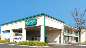 Un hôtel Quality Inn doté d’un toit végétalisé et de murs blancs, d’un parking et d’un arbre au premier plan.