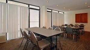 Une salle de conférence dotée d’une grande table, de nombreuses chaises et de grandes fenêtres équipées de stores.