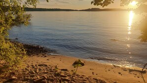 A beach with a clear view of the water and a distant shoreline. - Fredriksborg Hotel (Värmdö)