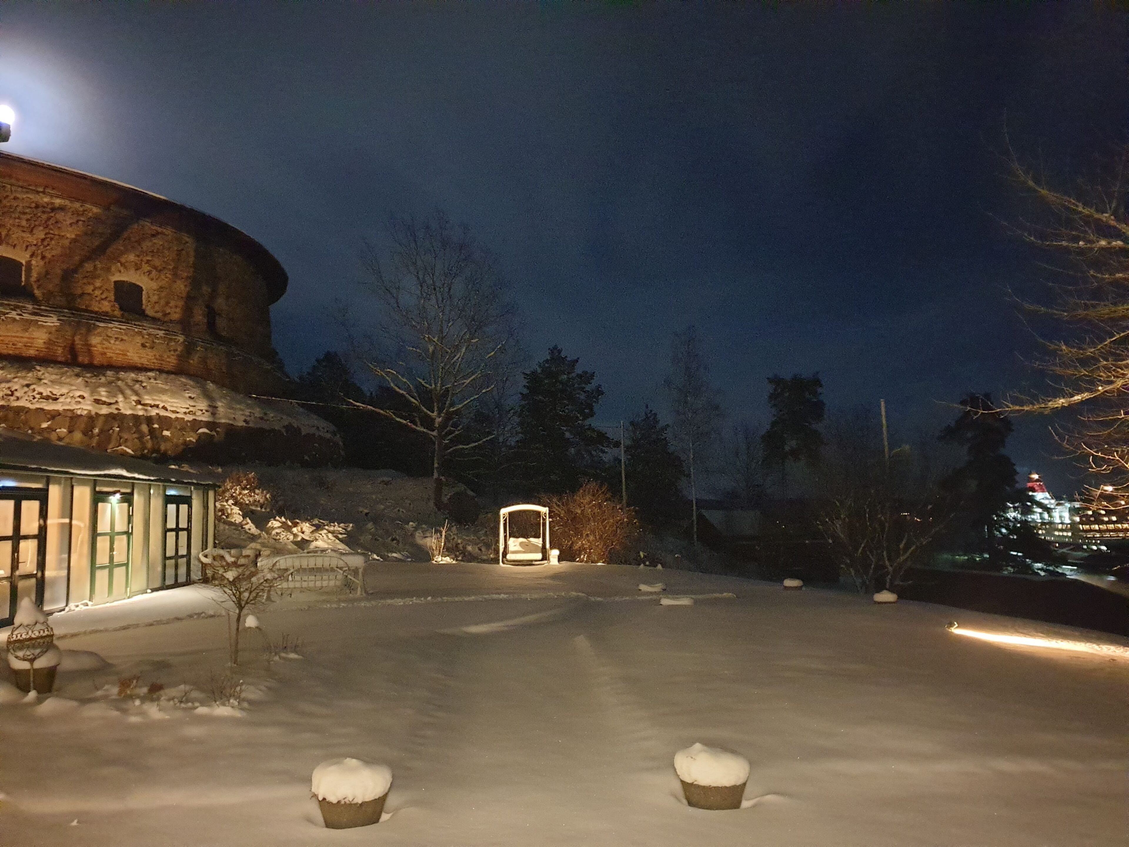 A snow-covered courtyard with a building featuring a circular structure and a traditional entrance.