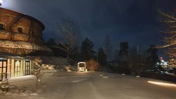 A snow-covered courtyard with a building featuring a circular structure and a traditional entrance.