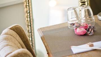 A wooden table with a mirror, two glasses, and a pink decorative item.