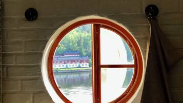 Una ventana redonda con vista a un edificio al otro lado del agua.