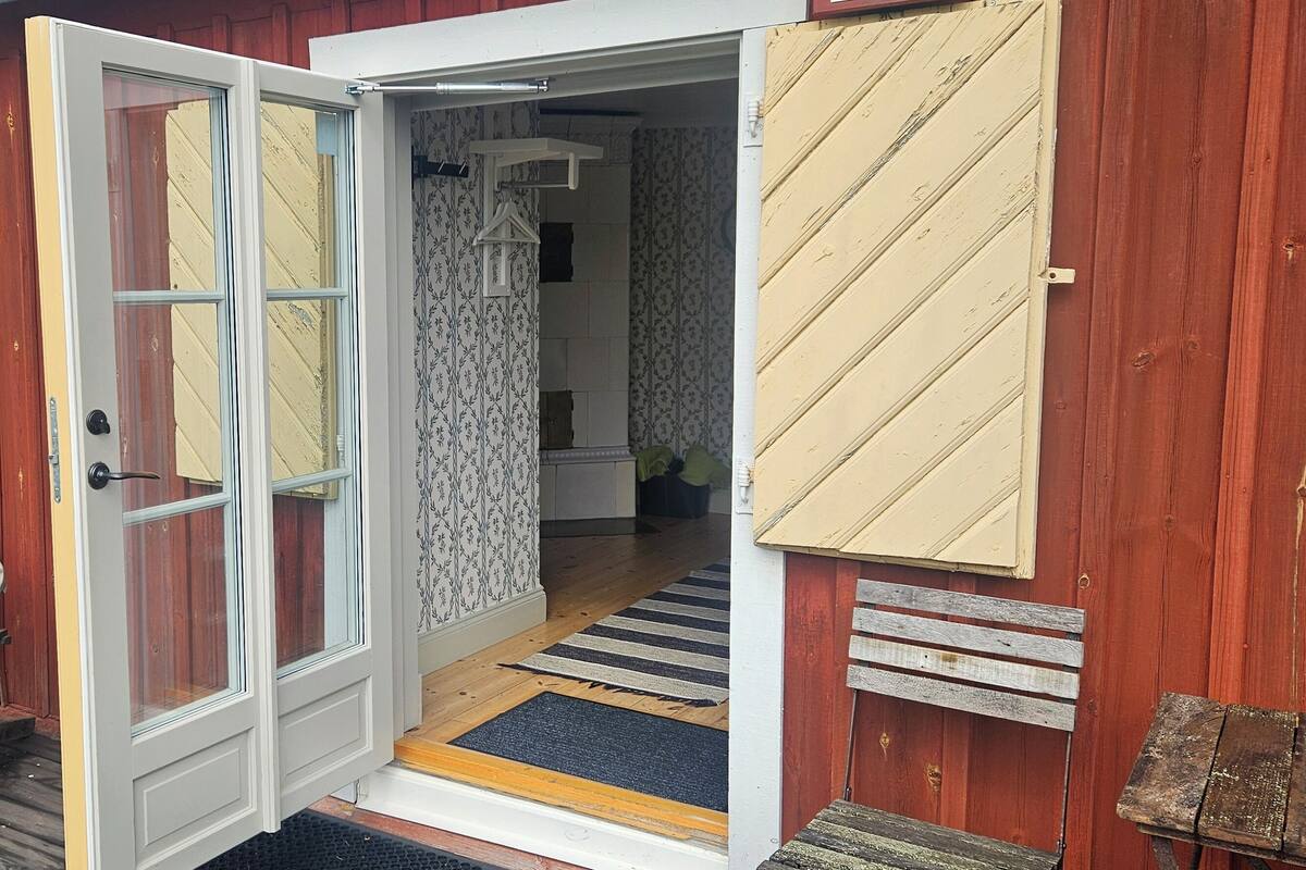 A wooden exterior with a door leading to a porch area.
