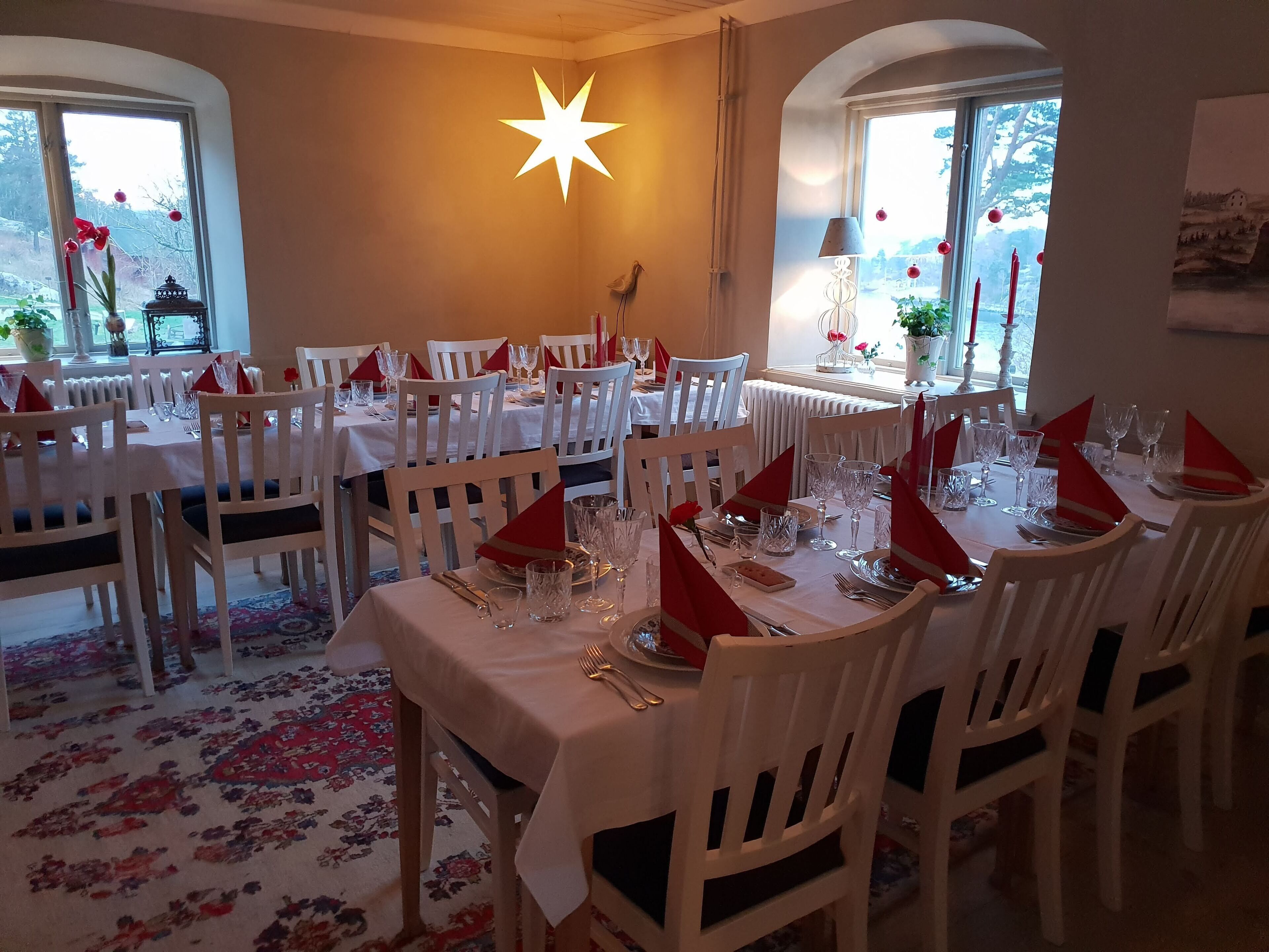 A dining area with multiple tables set for a meal, white chairs, and a star-shaped light fixture.