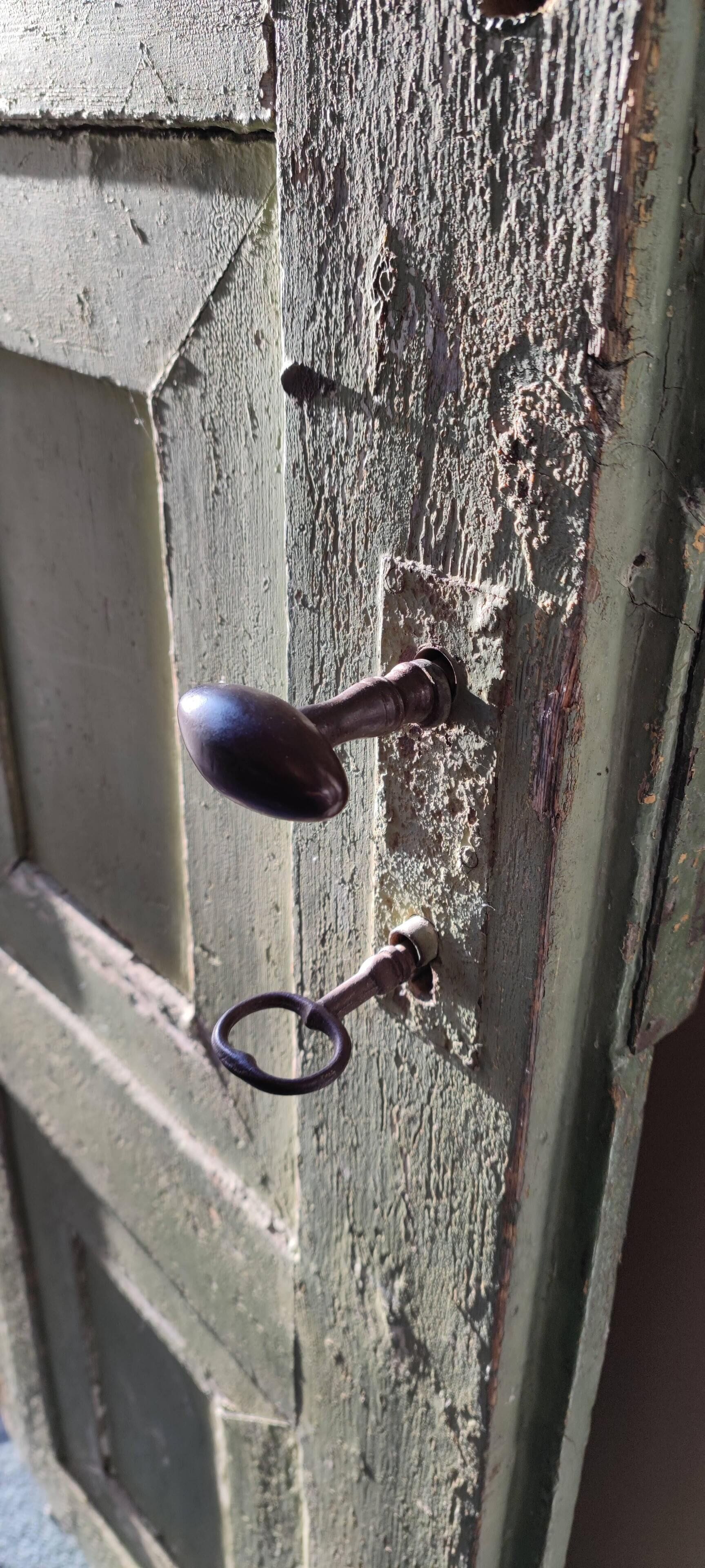 Primer plano de una puerta de madera desgastada, con un cerrojo y una cerradura metálicos.