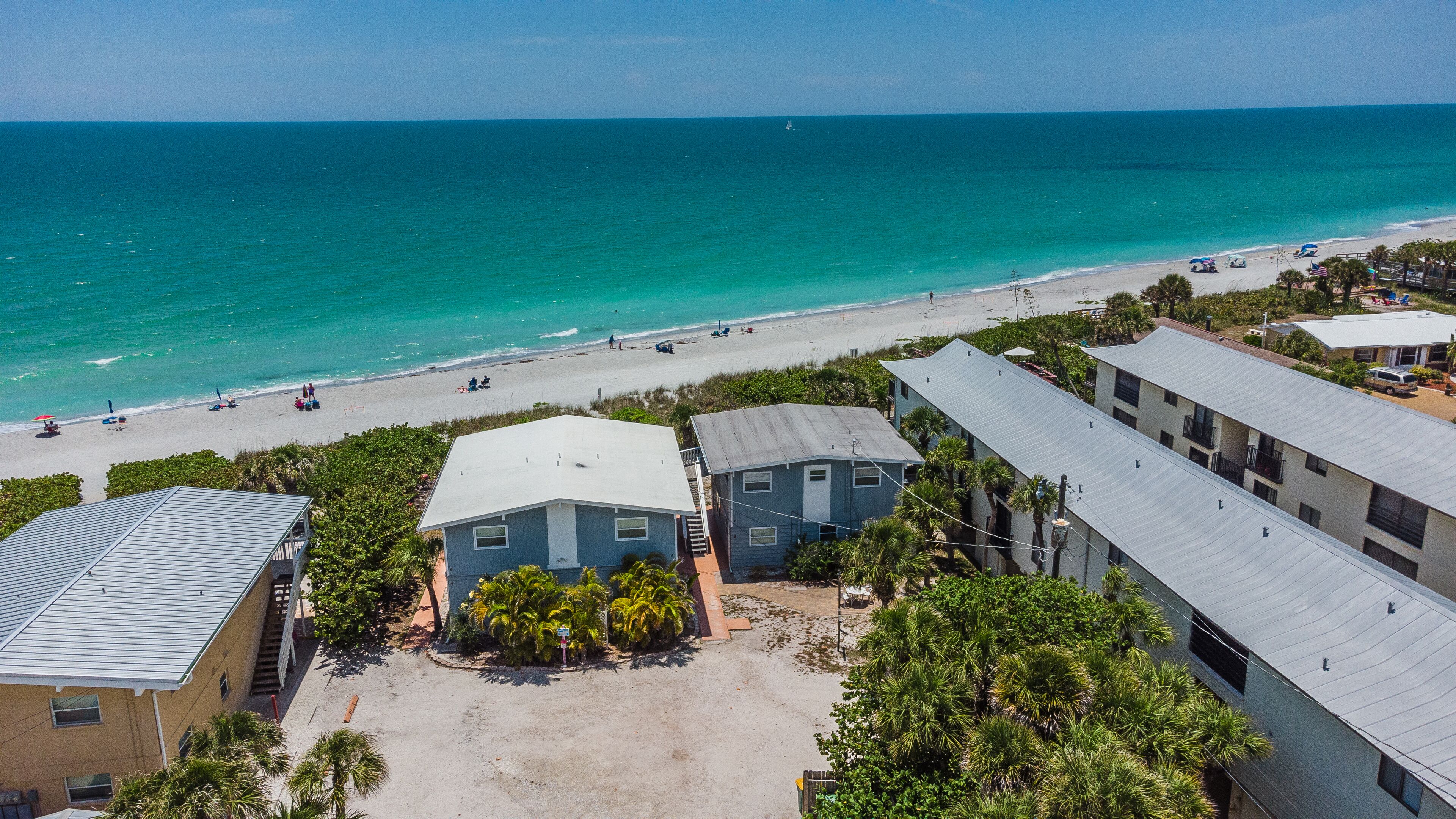 A beachfront property with multiple buildings, a sandy beach, and a view of the ocean.