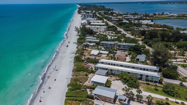 An aerial view of a coastal town with a beach, residential buildings, and a marina.