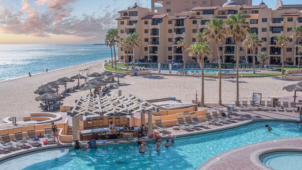 A resort with a pool, beach, and palm trees.