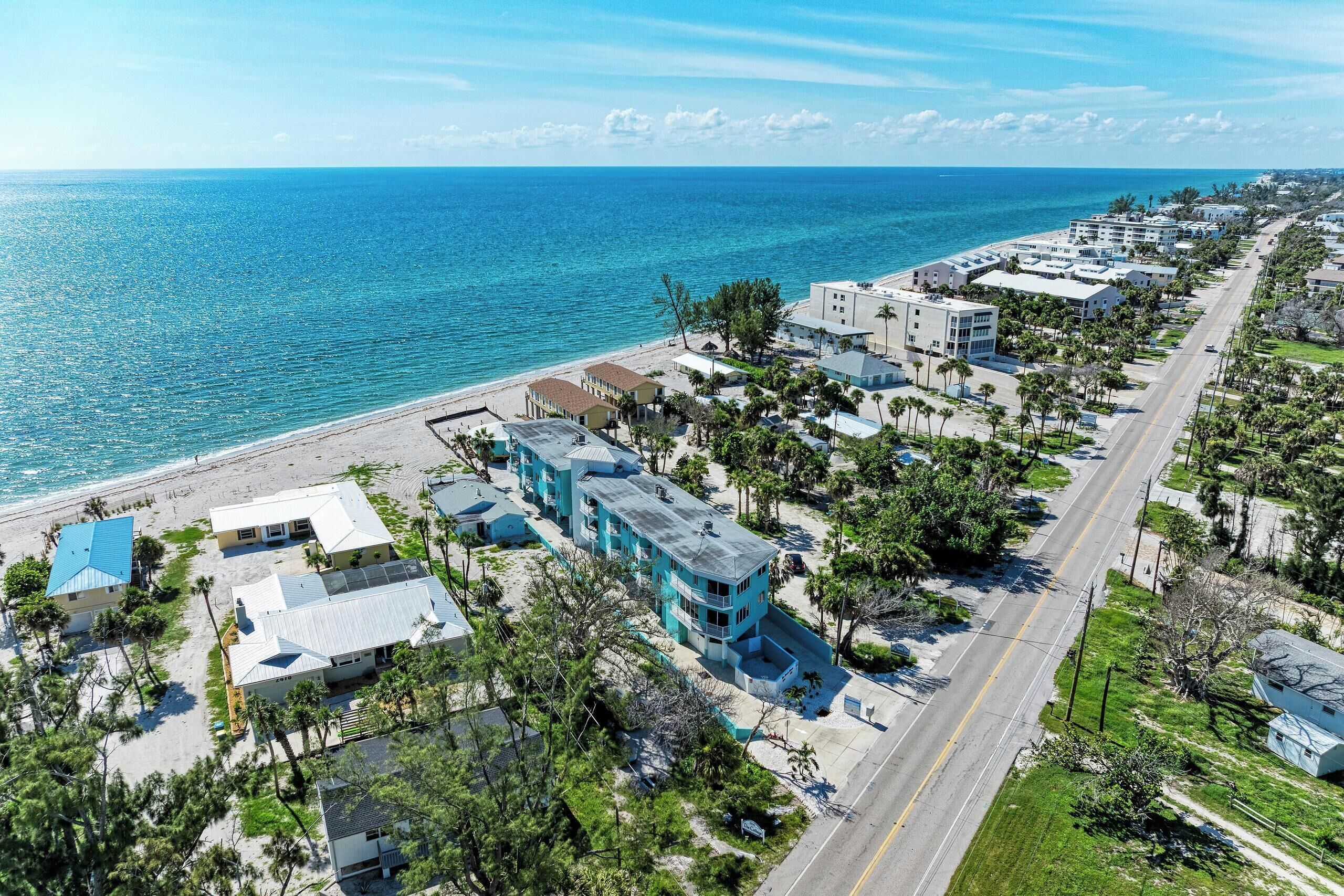 A coastal residential area with a beachfront, multi-story buildings, and a road running parallel to the beach.
