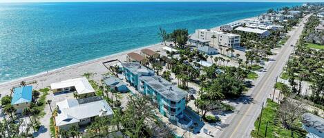 A coastal residential area with a beachfront, multi-story buildings, and a road running parallel to the beach.