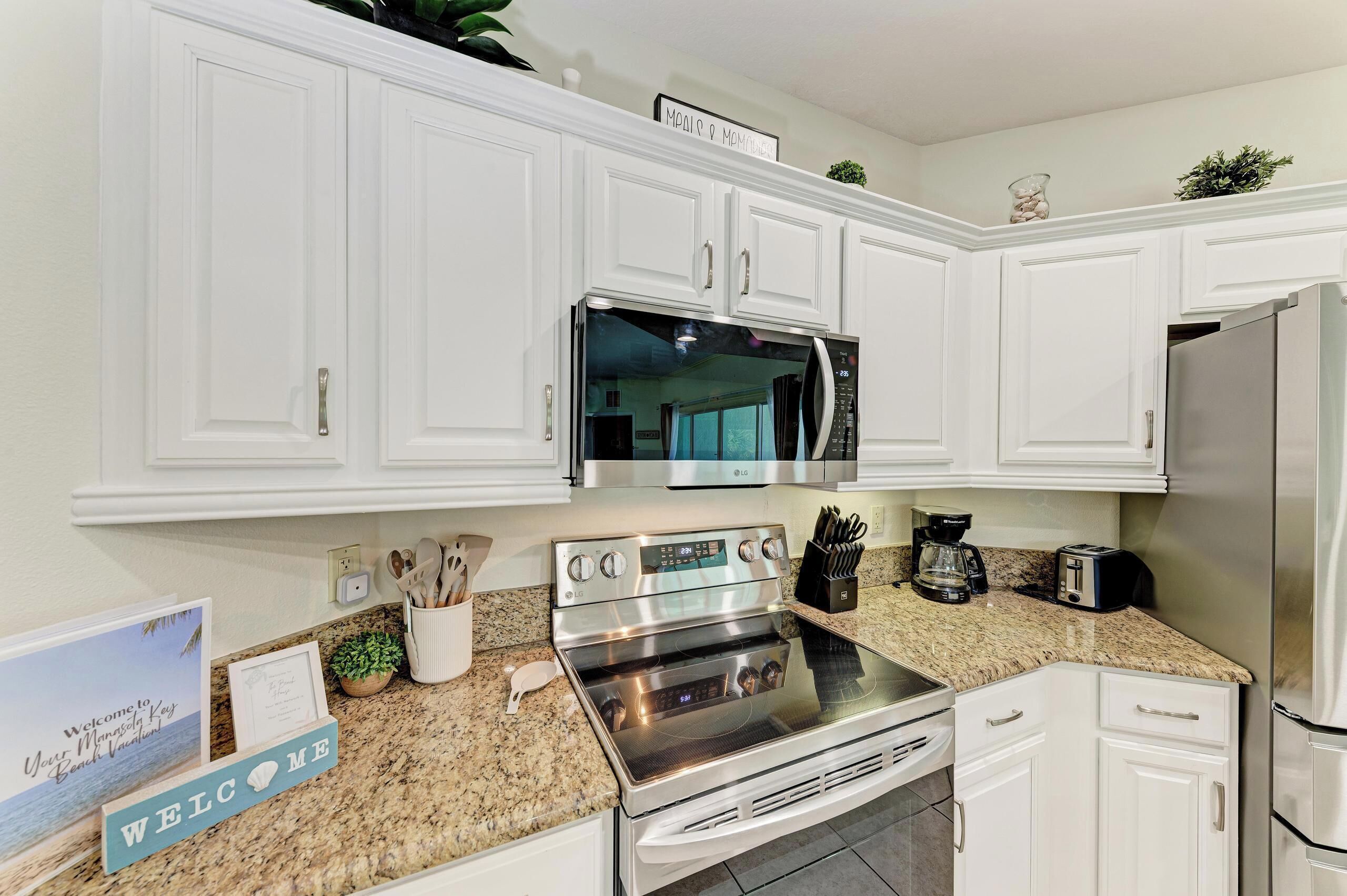 A kitchen with white cabinets, stainless steel appliances, and granite countertops.