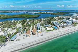 An aerial view of a coastal resort with beachfront properties, a marina, and a marina with boats.