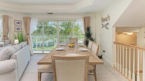 Un coin repas avec une table dressée pour quatre personnes, un canapé et un escalier.
