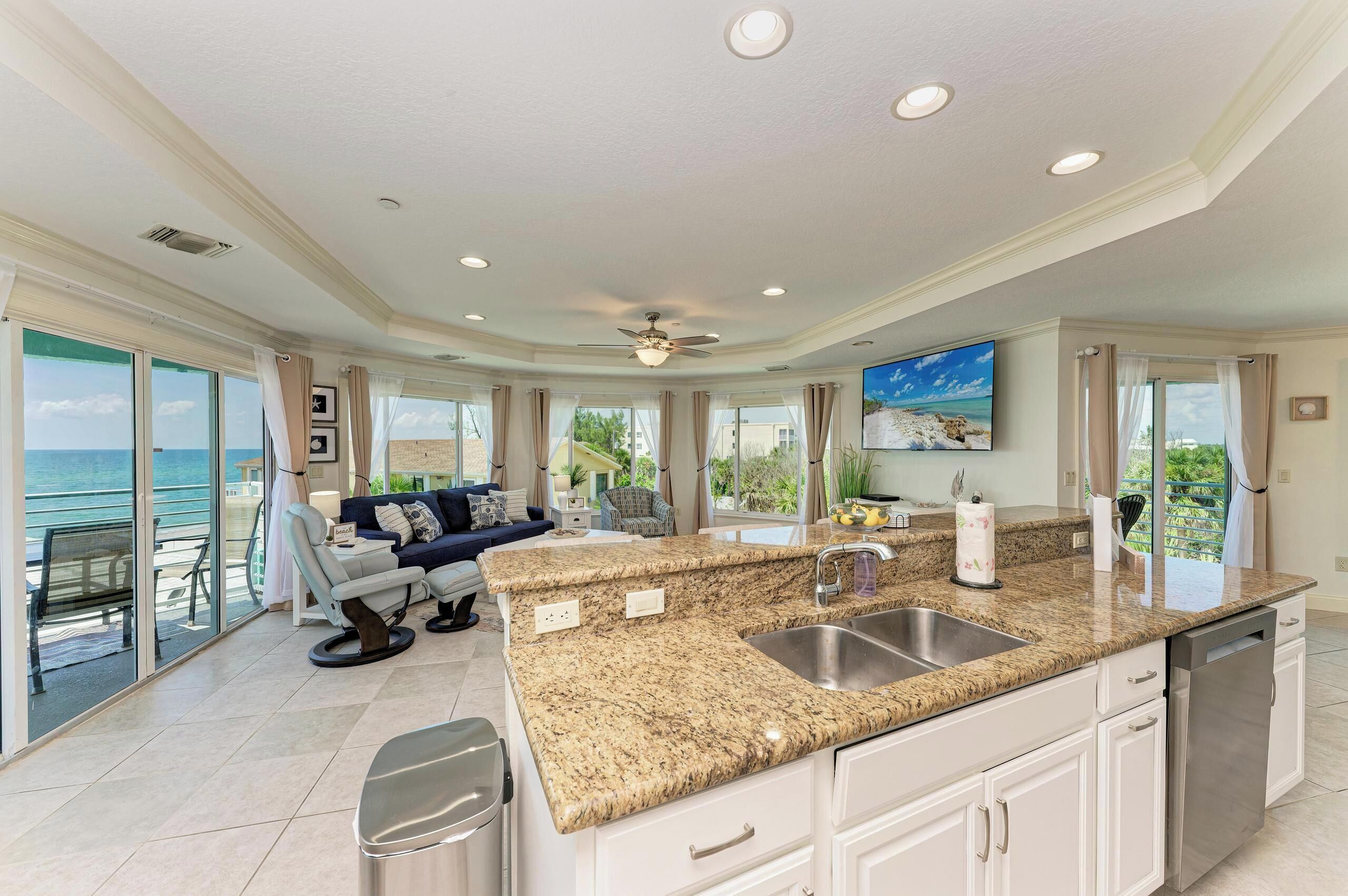 A spacious kitchen with granite countertops, a built-in dishwasher, and a large island with a sink.