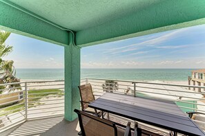A balcony with a view of the beach and ocean, furnished with a table and chairs. - 3 Bedroom-Beachfront Condo with Most Amazing Sunset Views of the Gulf (Englewood)