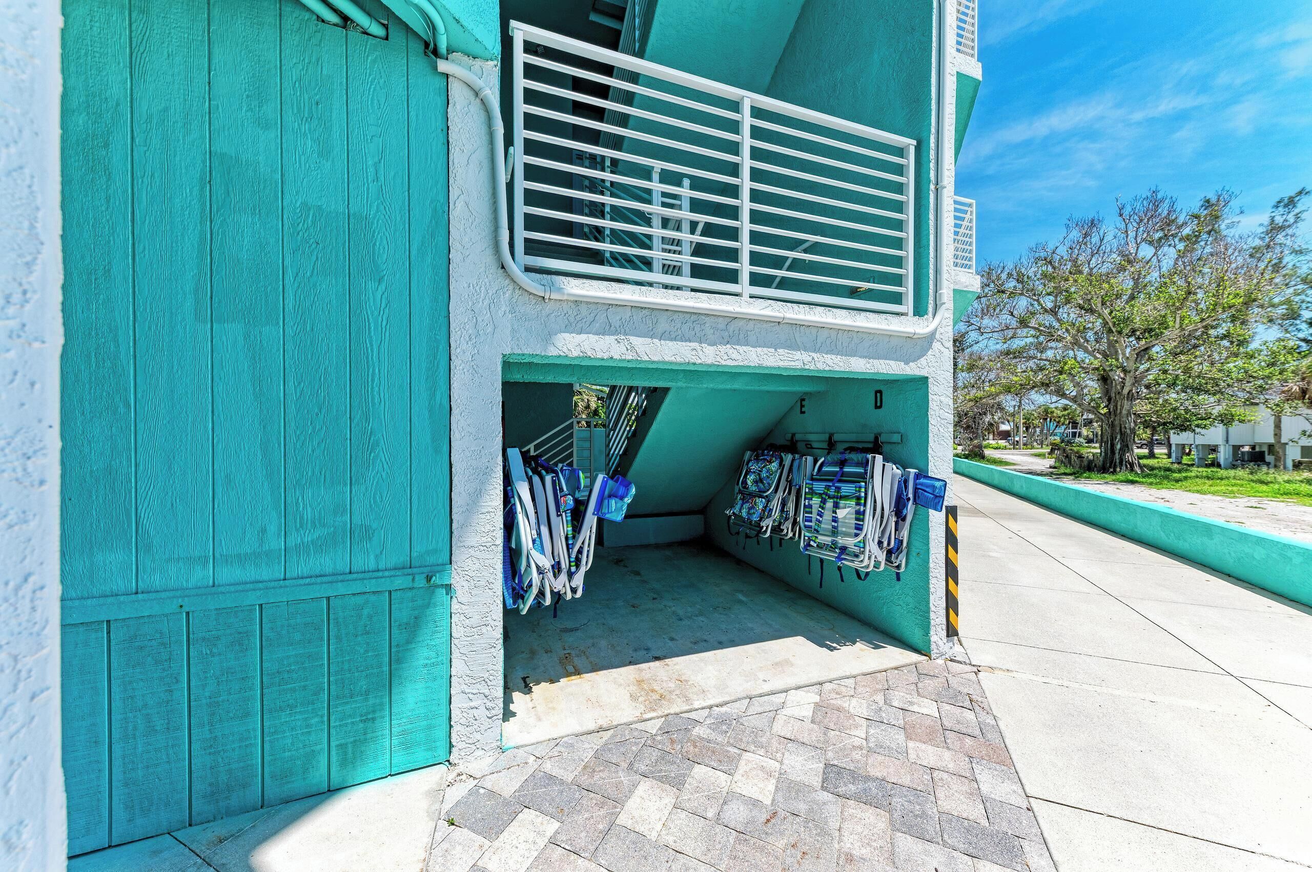 A building with a teal exterior, a balcony with a metal railing, and a ground-level entrance with a door.