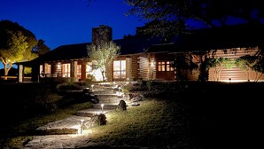 A log cabin with a stone staircase leading to the entrance, surrounded by trees and a well-lit garden. - River l Resort Pool l Lake l Firepit l HOT TUB (Ingram)
