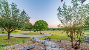 A landscaped area with a stone pathway, trees, and a grassy field. - River l Resort Pool l Lake l Firepit l HOT TUB (Ingram)